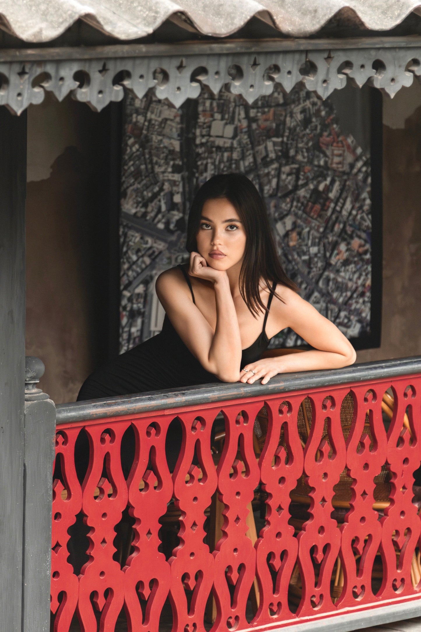 Woman sitting on a balcony with decorative railing and patterned wall behind her. Dtalat Noi & So Heng Tai Photoshoot. Bangkok Photoshoot by Photographer Nadya Shell