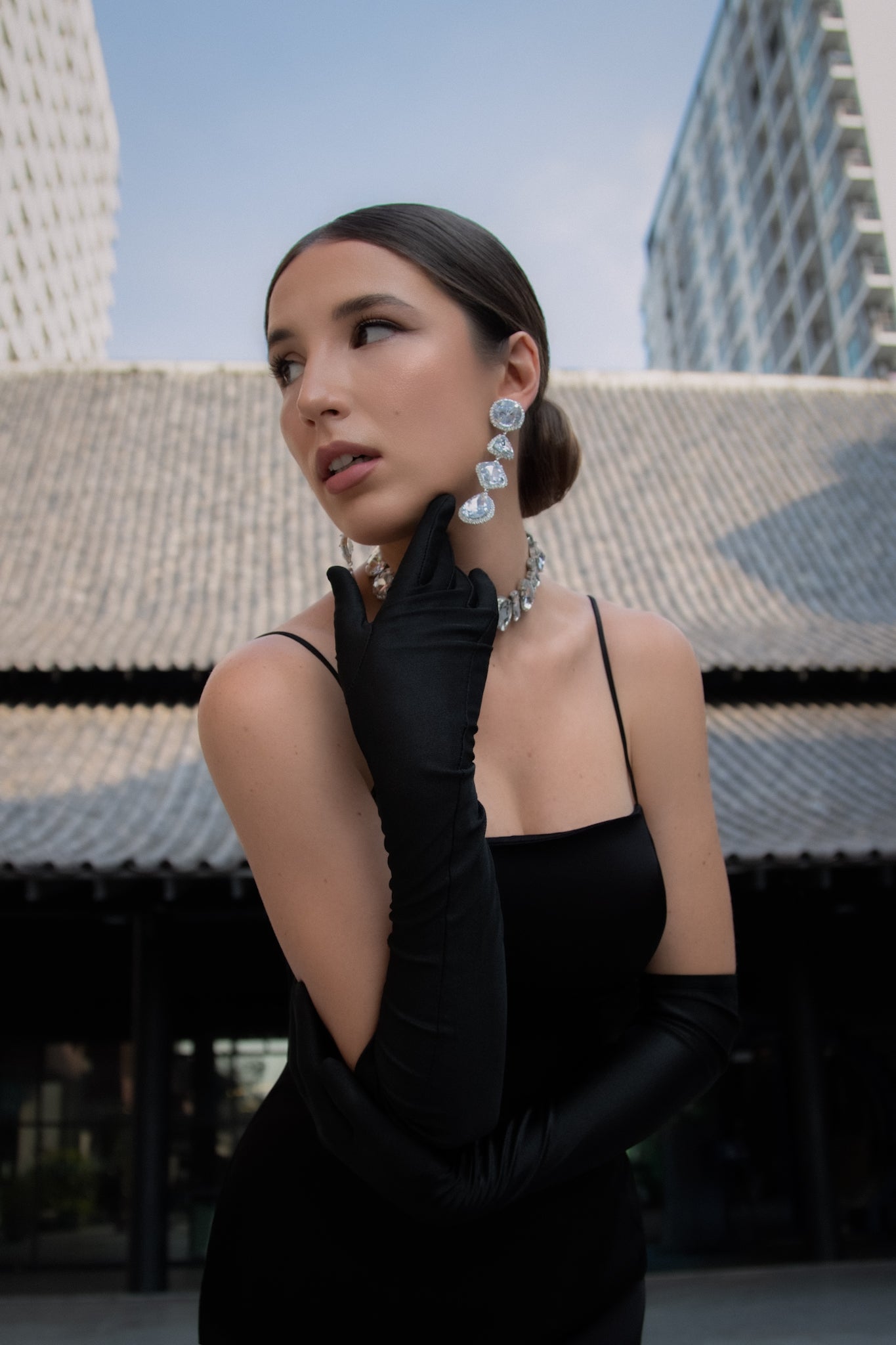 Woman in black dress and gloves with earrings, standing in an urban setting. Bangkok Dragontown Photoshoot by Photographer Nadya Shell