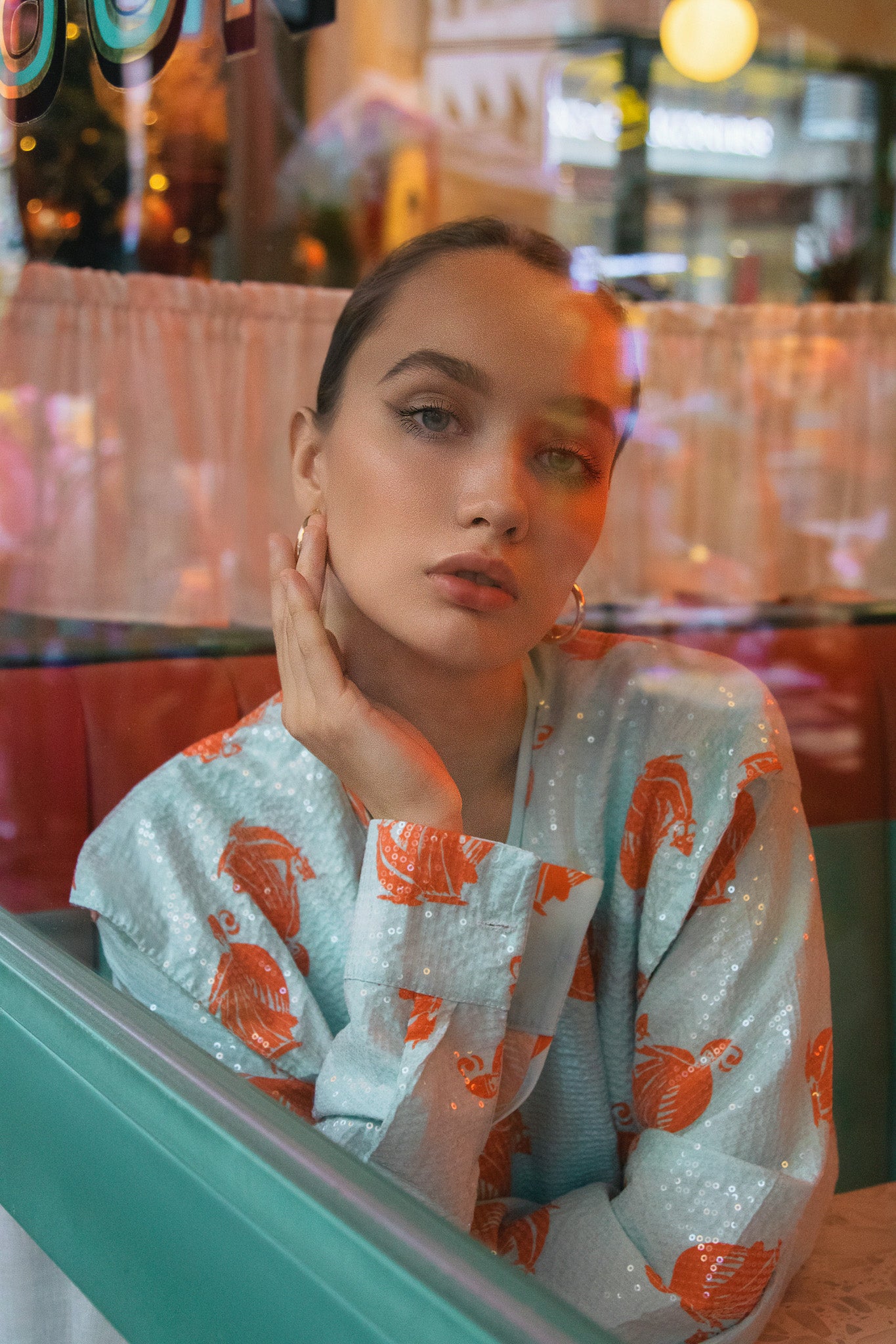 Woman sitting in a restaurant booth wearing a light blue kimono with orange patterns. Bangkok Chinatown Photoshoot by Photographer Nadya Shell