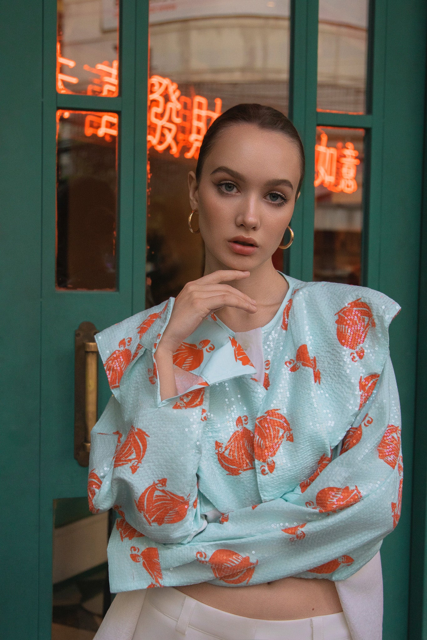 Woman wearing a light blue top with orange floral patterns in front of a neon sign. Bangkok Chinatown Photoshoot by Photographer Nadya Shell