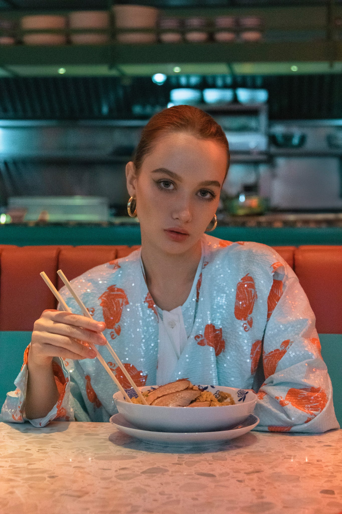 Woman in a restaurant setting holding chopsticks over a bowl of food. Bangkok Chinatown Photoshoot by Photographer Nadya Shell