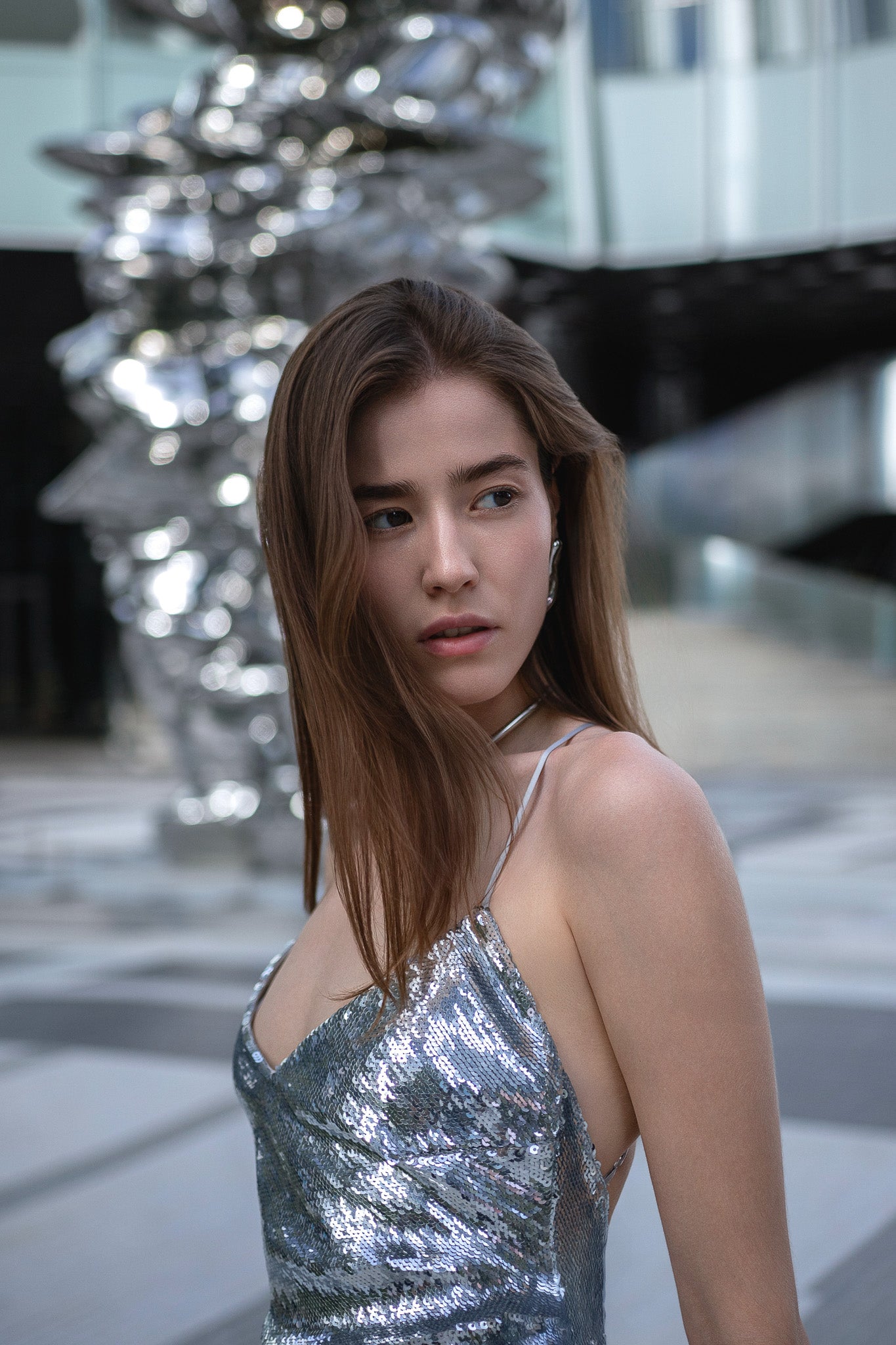 Woman in a silver sequin dress standing in front of modern architectural elements. One Bangkok Photoshoot. Bangkok Photoshoot by Photographer Nadya Shell
