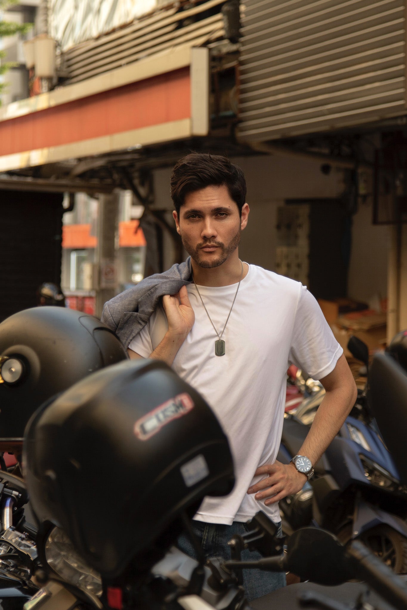 Man standing next to a motorcycle in an urban setting. Bangkok Photoshoot by Photographer Nadya Shell