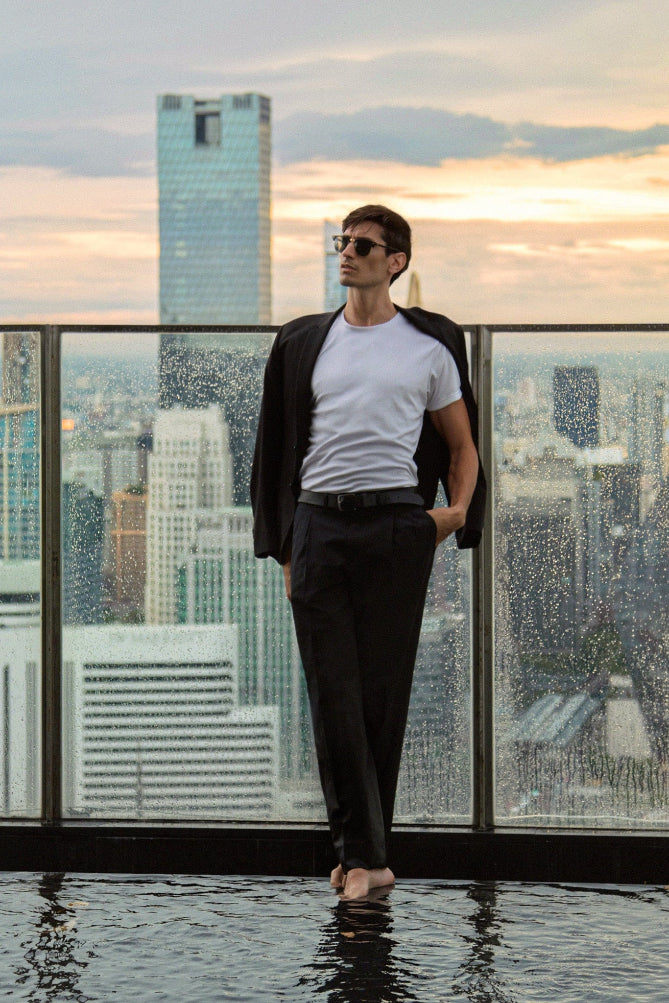 Man standing on a skyscraper rooftop with the Bangkok city skyline in the background. Bangkok Photoshoot by Photographer Nadya Shell